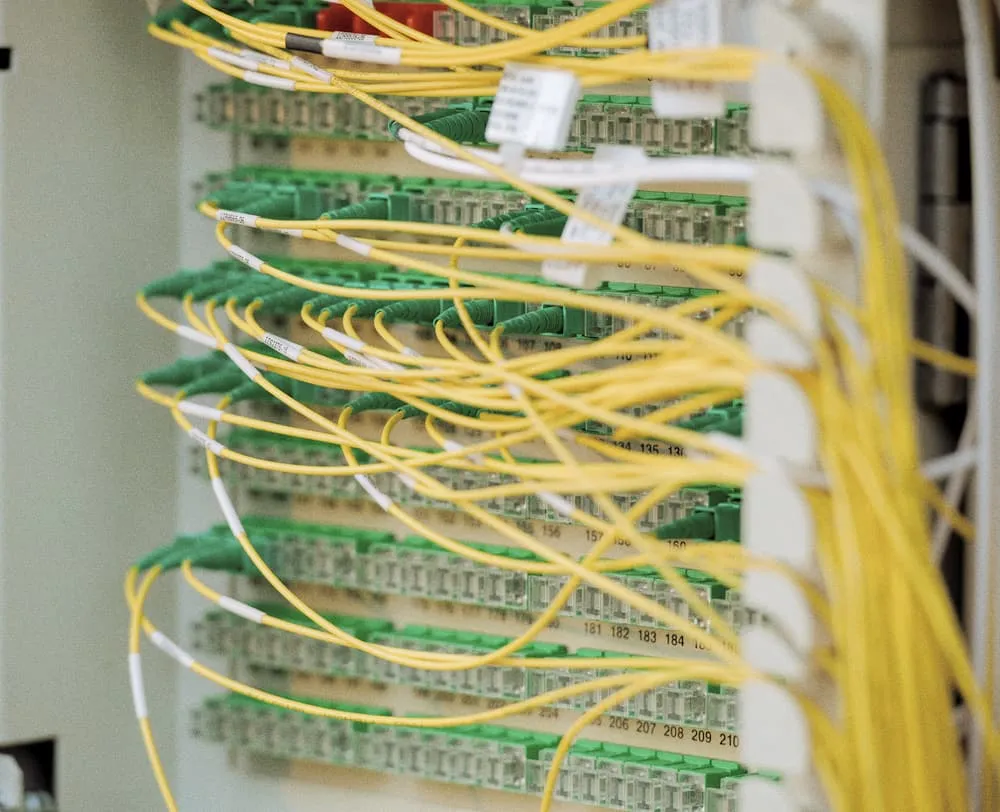 Une armoire de brassage, fibres optiques jaunes et câbles réseau rangés