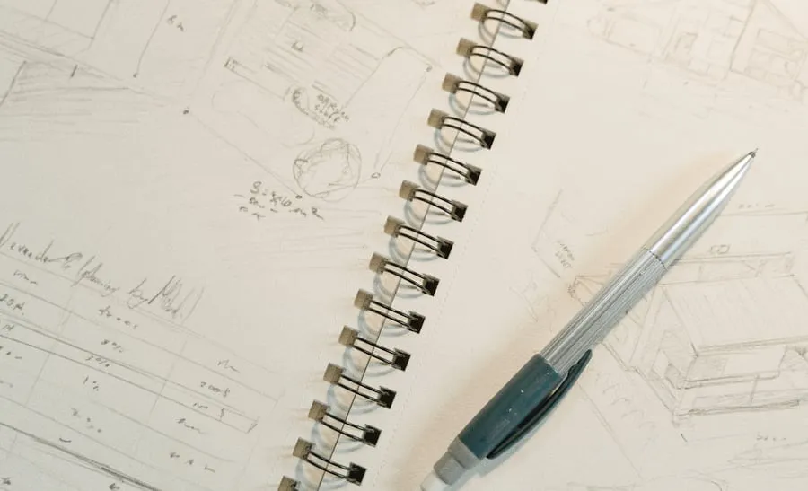 Un carnet ouvert sur un croquis au crayon, un porte-mine posé dessus