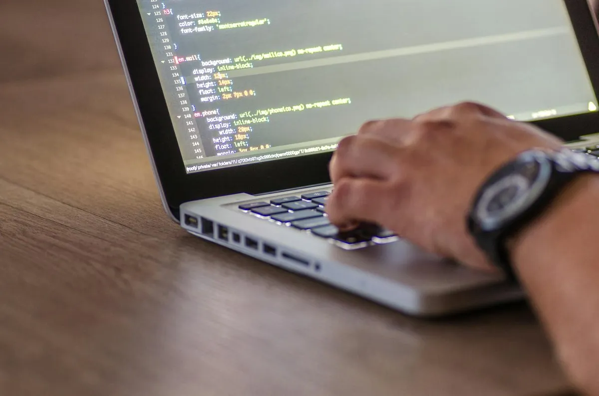 A hand typing on a laptop open on CSS code
