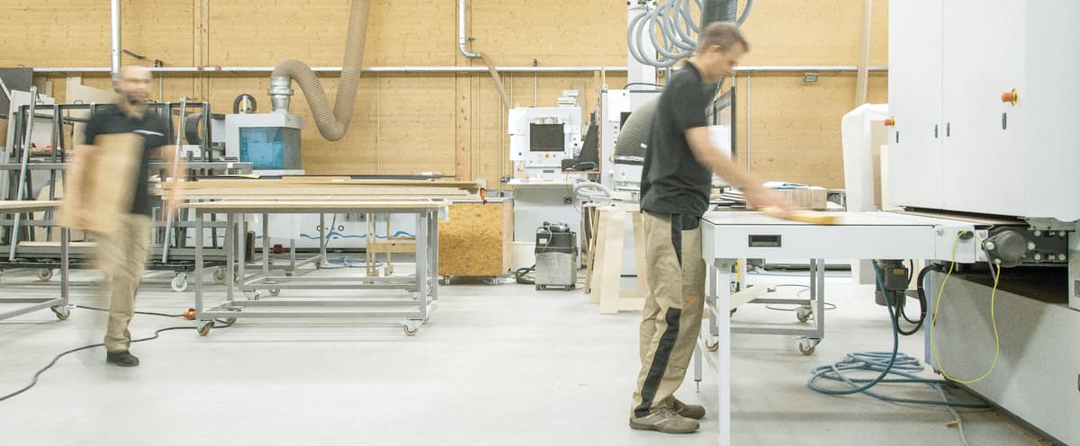 Atelier d'une PME industrielle, deux personnes au travail entre les établis
